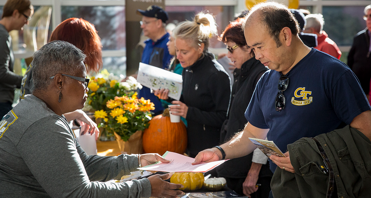 Parents and family take brochures from volunteers during a GT Family weekend.