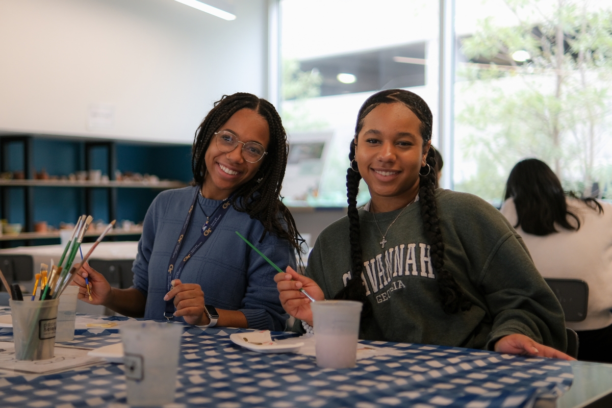 Two young women sit a table with craft supplies